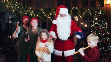 Noel Baba, evde Noel ağacıyla müzik aleti çalan çocuklarla dans ediyor..