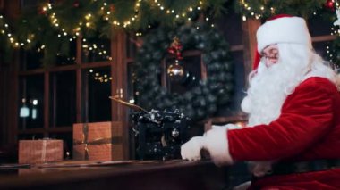 Santa Claus in a New Year's residence sitting at a table reads letters through a magnifying glass. Santa Claus Village.
