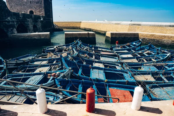 MOROCCO, ESSAOUIRA - MARCH 14, 2020: Blue fishing boats with children near the fortress of the port of Essaouira.