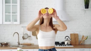 Ellerinde portakal dilimleri olan pozitif gülümseyen bir kız gözlerini kapatıyor..