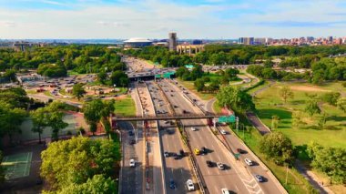 Grand Central Parkway 'de yoğun bir trafik var. Bir üst geçidin ve çevrenin yeşil ağaçlarla çevrili olduğu bir kavşağın hava görüntüsü. Queens, New York Şehri. Şehrin Panoraması.