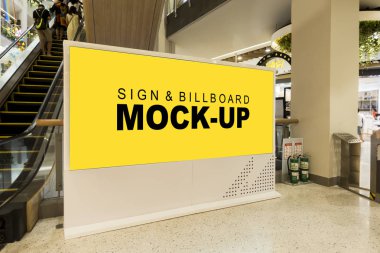 Alışverişte yürüyen merdivenin yanındaki maket boş sarı ekran reklam panosu
