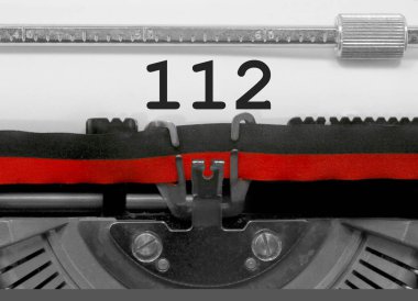 Eski bir daktilo tarafından beyaz kağıda yazılı 112 numarası metni