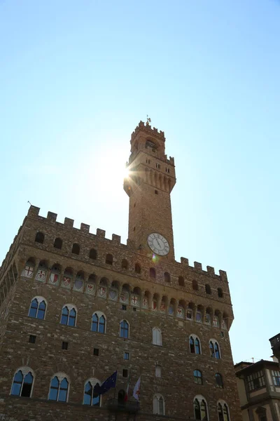 太陽光線は シニョーリア広場と呼ばれる都市の主要な正方形のイタリアのフィレンツェのヴェッキオ宮殿の高塔から芽します — ストック写真