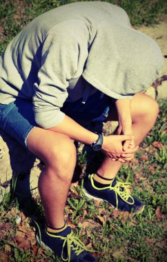 parkta dayak sırasında başını kaputa ile depresif adam