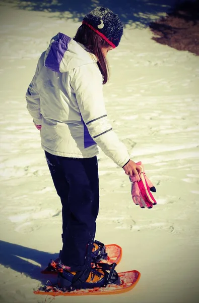 小女孩站在雪地上检查穿雪鞋前的老式效果 — 图库照片