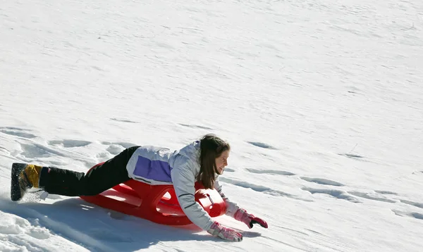 柔らかい白い雪ですべりそりの上に横たわる少女を下る — ストック写真