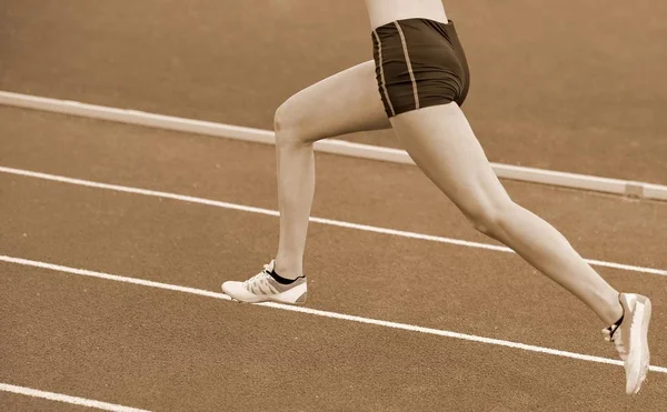 长腿赛跑者赛跑在运动的轨道与棕褐色色调 — 图库照片