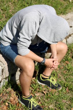 gri sweatshirt ve başını kaputa depresyonda çocuk