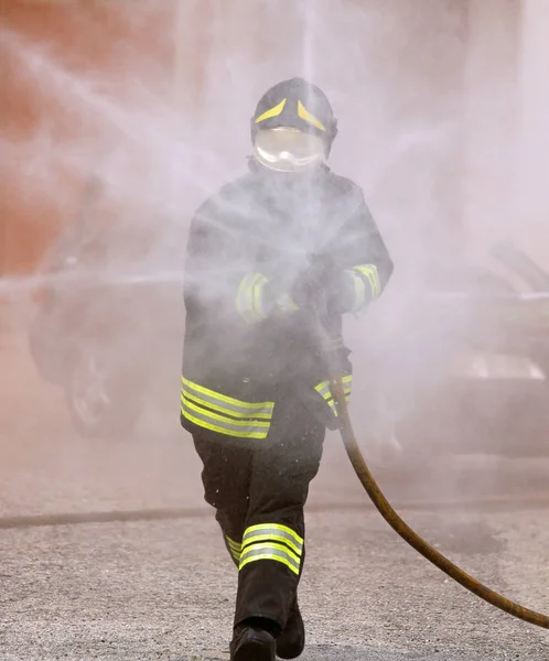 firefighter with a protective helmet uses a foaming agent to extinguish a wildfire