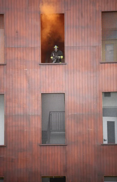 fireman protrudes from a window of a burning building