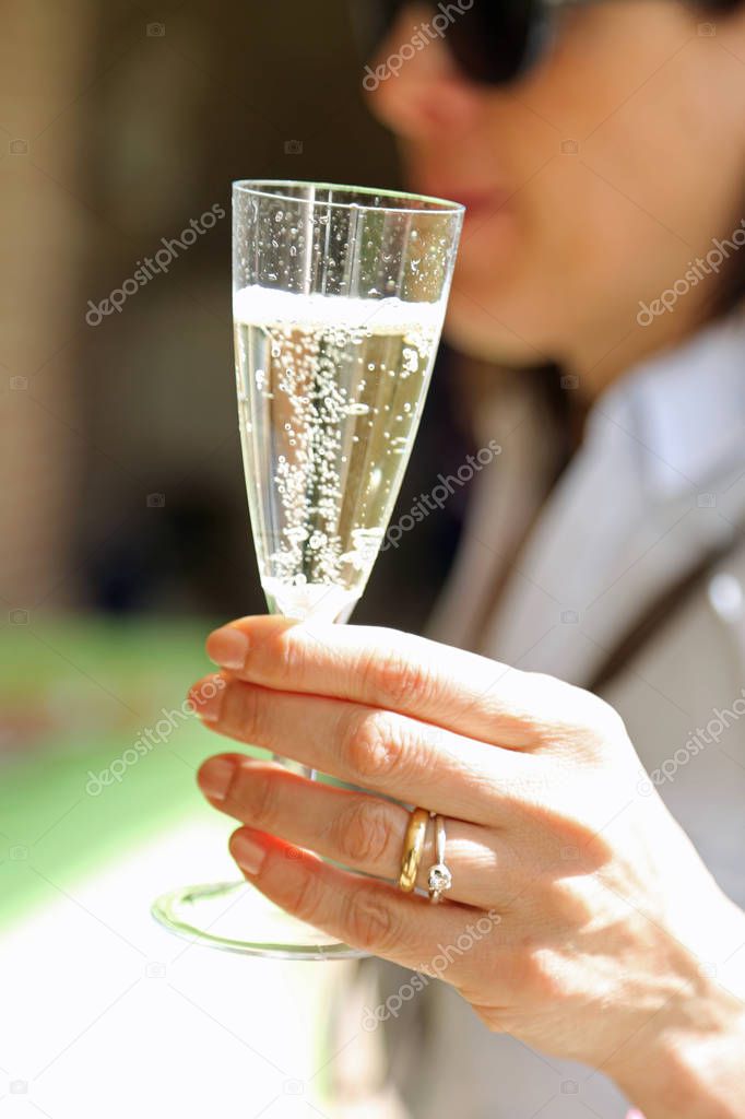 Hand of the newly married wife with the engagement ring that lifts the glass of wine to toast the wedding