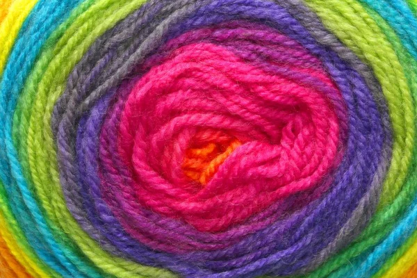 Many woolen threads wrapped around each other to form a colored target with the colors of the rainbow