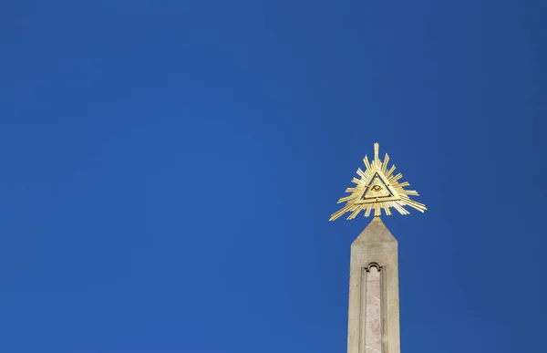 Obelisk with above the golden eye of providence which is a symbol with a triangle and within the eye of God