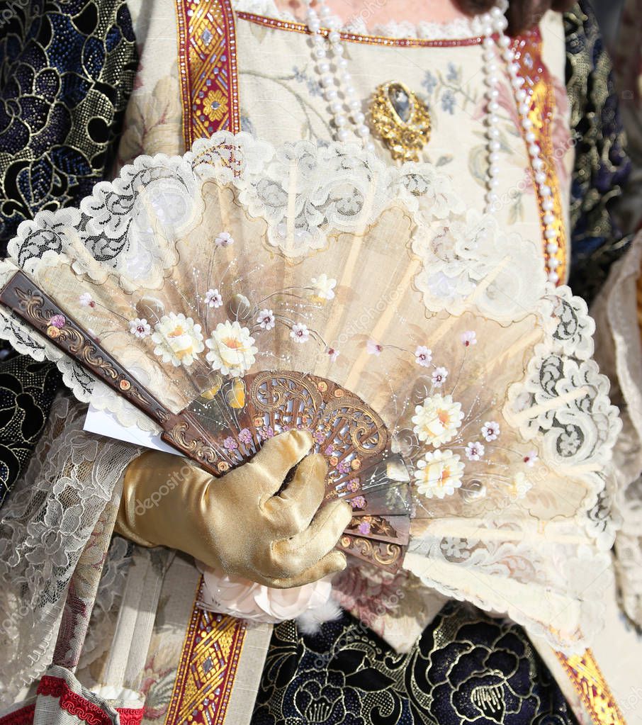 Noble Woman with the luxurious dress while airing with the fan held by a gloved hand