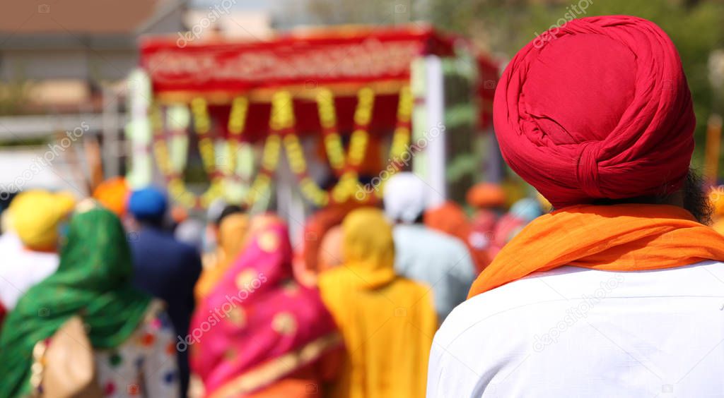 Sikh man with red turban with many people during a religious ceremony