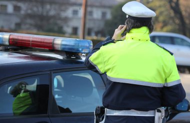 polis arabasını yakınındaki sokakta bir cep telefonuyla konuşuyor