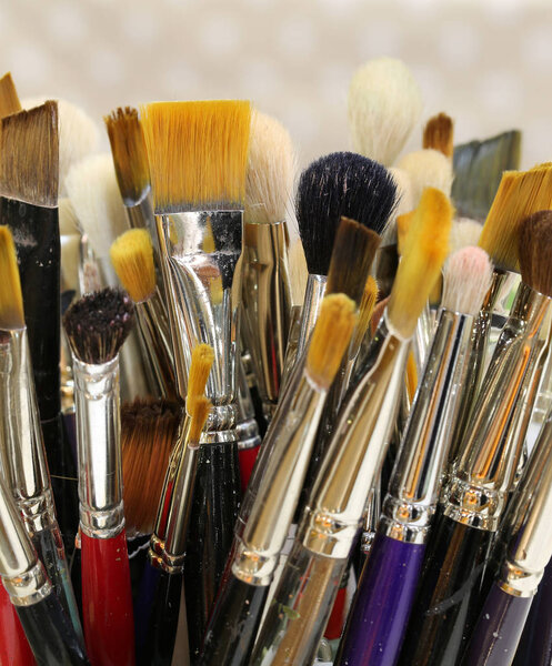 brushes of various shapes and sizes to paint paintingsin the studio of a painter