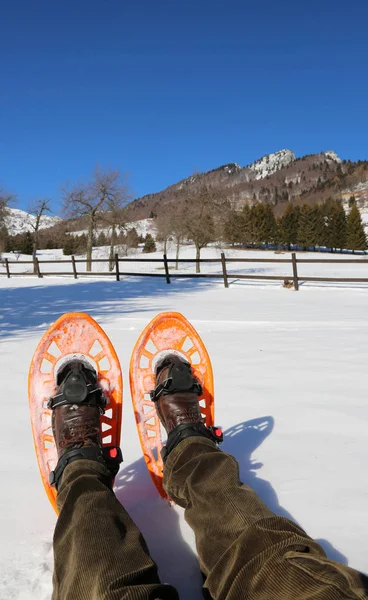 徒步旅行者与橙色穿雪鞋在山的远足以后休息在雪 — 图库照片
