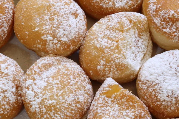 Background of small donuts stuffed with cream and jam and sprinkled with powdered sugar