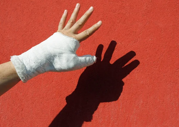 赤い壁を背景に国内事故に続く漆喰手首 — ストック写真