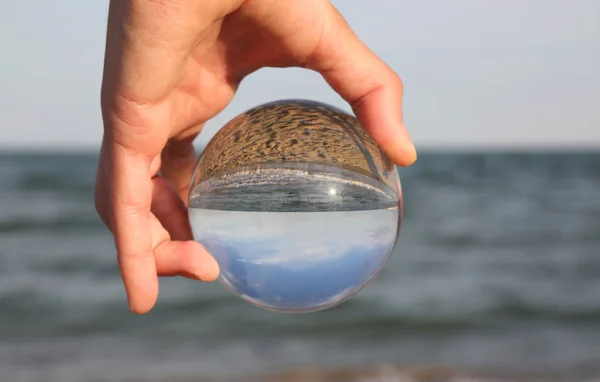 hand of a boy with a big sphere in glass by the sea