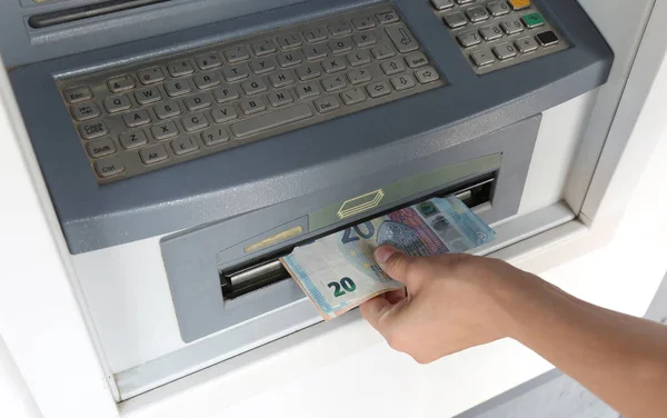 withdrawing cash from an ATM with euro banknotes