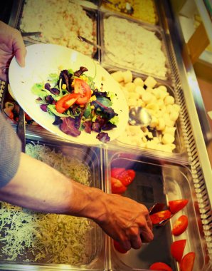 Çalışan Self-servis restoran dolgular marul ve domates ile ve Mısır vintage etkisi ile öğle yemeği molası sırasında