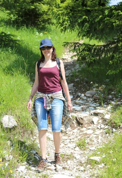 青い帽子と山脈の若い美しい女性が歩く — ストック写真