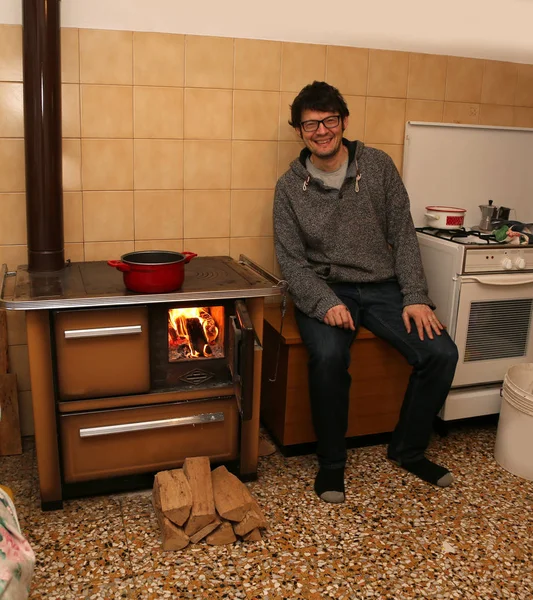 若い男と台所で火の古代木バーナー — ストック写真
