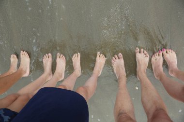 Yaz aylarında deniz kenarında yalınayak ayaklı beş kişilik aile