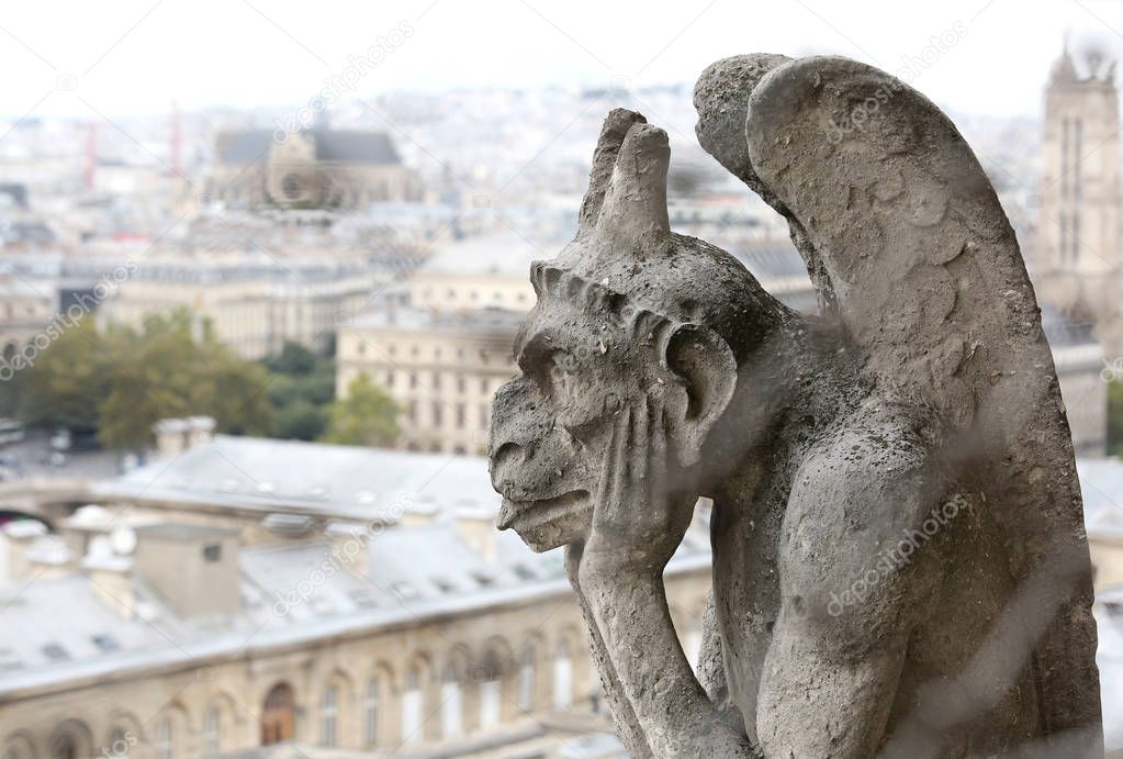 thinking figure called Chimera or grotesque with wings in Paris from Bell tower of Basilica of Notre Dame