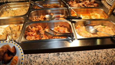 many trays with fried food in a self service Chinese restaurant clipart