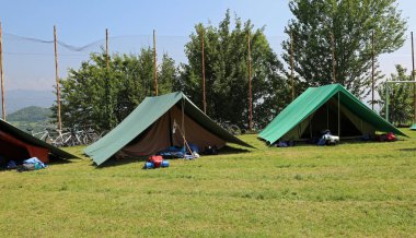 two green tents mounted by scouts in a meadow to spend the night clipart