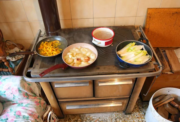 many pots on the wood burning stove in the kitchen of an old house