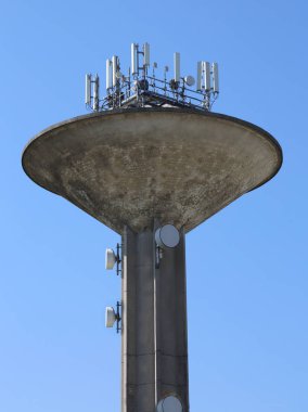 surge tank of an aqueduct system and many telecommunication antennas with blue sky on background clipart