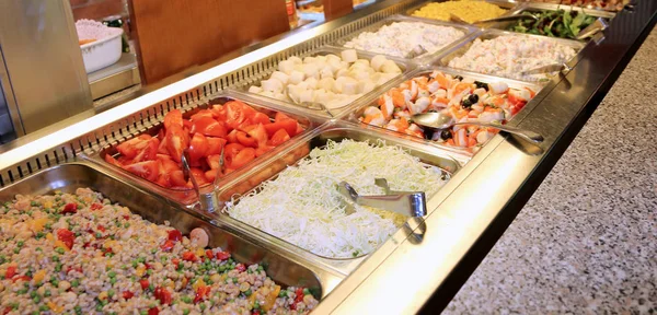 trays full of pasta dishes and side dishes of vegetables with tomato, fish salad and other goodness