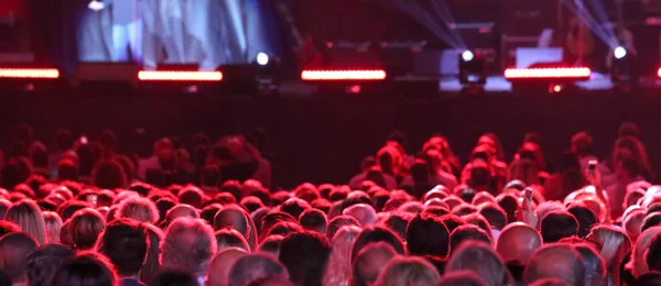 heads of many people during live outdoor concert with many lights on stage