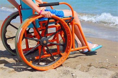 Çocuk bir özel tekerlekli sandalyede hareketinin sorunları ile denizin sahilden gözlemlediği