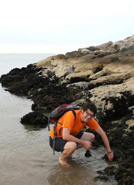 男が海で岩に多く黒ムール貝を取る — ストック写真
