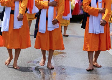 Sih din uzun turuncu giysileri ile birçok erkek çıplak ayakla kılıç ile yürümek