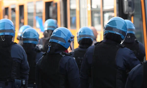 many policemen in riot gear control buses with hooligans