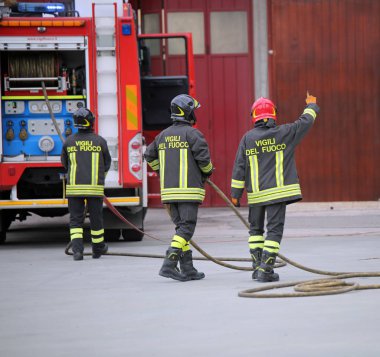 Italia, İtalya - 10 Mayıs 2018: üç İtalyan itfaiye ve yangın kamyon itfaiyeciler İtalyan dilinde bir pratik egzersiz sırasında demek üniforma ve metin Vigili del fuoco ile. Kırmızı kask ile itfaiyeci lideridir