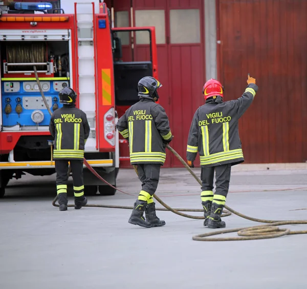 意大利意大利 2018年5月10日 三名意大利消防队员和带有制服和文字的消防车 这意味着消防员在一次实际演习中使用意大利语 戴红色头盔的消防员是领队 — 图库照片