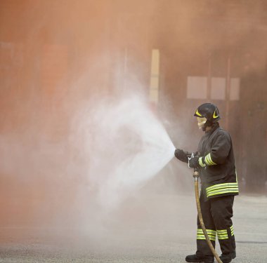 Firefighter bir köpük musluğu ile büyük bir yangın söndürür