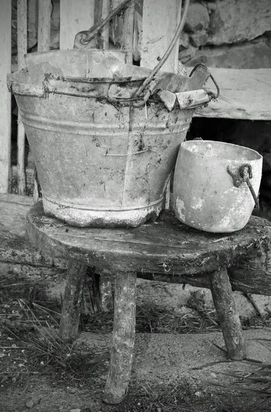 破碎的锡桶和铝锅在旧的稳定与黑色和效果的凳子 — 图库照片