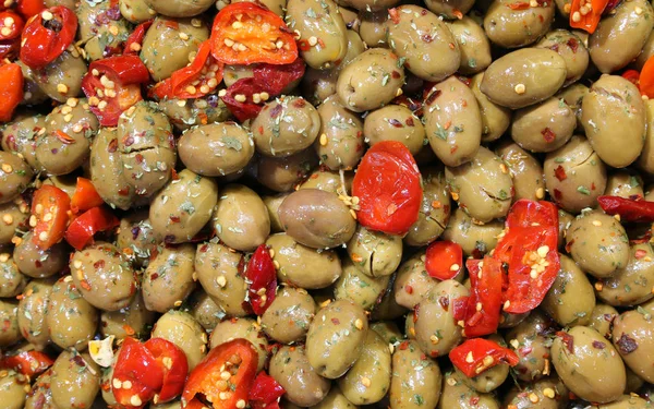 在意大利南部的意大利食品展台上出售的盐水中的绿色橄榄和一些红辣椒 — 图库照片