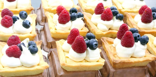 many pastries stuffed with cream and berries for sale in a pastry shop