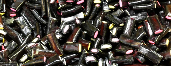 Achtergrond Van Zwarte Drop Snoepjes Gevuld Met Gekleurde Suiker — Stockfoto