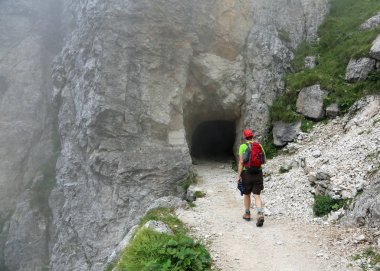Uzun yürüyüşe çıkan kimse bir sırt çantası ile bir yokuş yukarı dağ yolunu yürür